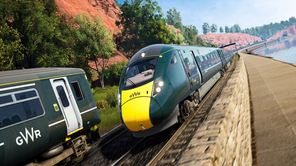 Train Sim World avec un train vert qui circule sur des rails prés d'un lac