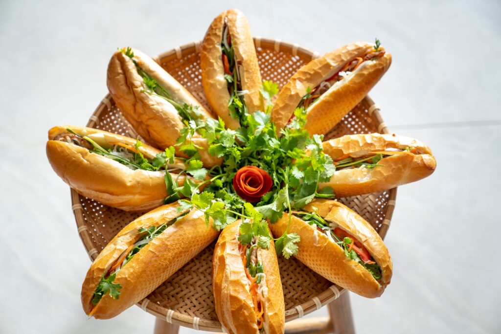 Banh mi disposé en éventail sur un tabouret en osier avec une rose et de la coriandre
