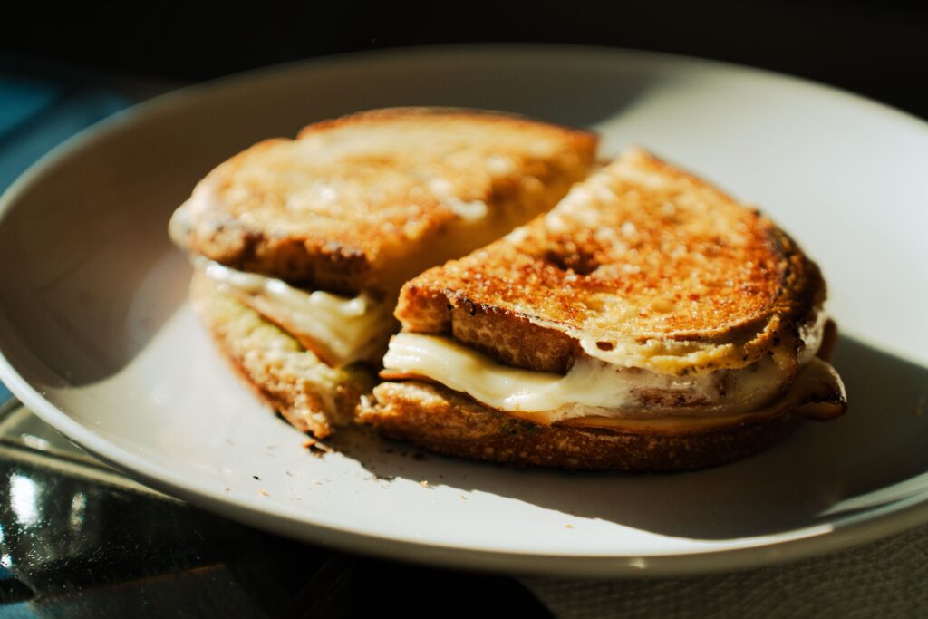 Grilled cheese coupé en deux dans une assiette avec du pain et du fromage
