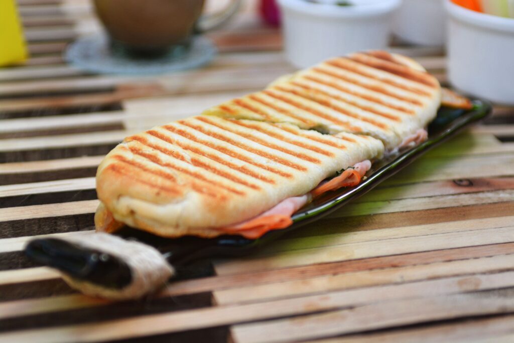 Panini au jambon placé sur une table en bois et grillé
