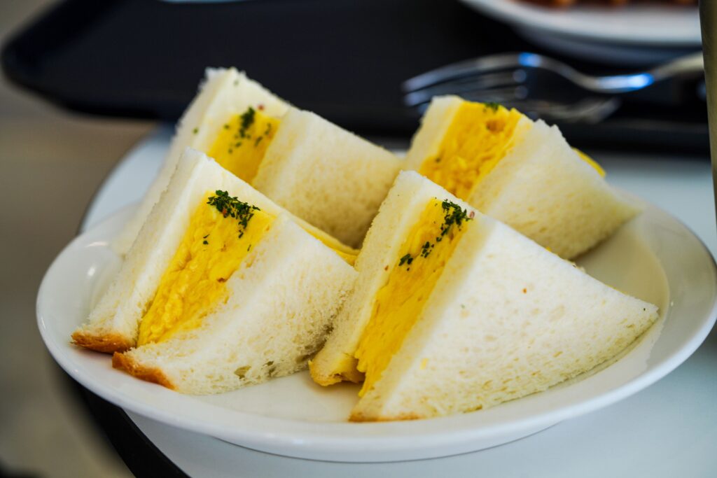 Egg sandwich ou tamago sando avec du pain de mie et des oeufs coupé en quart sur une assiette